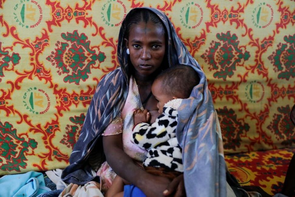 Una donna tiene un bambino all'interno della scuola secondaria di Adiha, che è stata trasformata in un rifugio temporaneo per gli sfollati a causa del conflitto, nella città di Mekelle, regione del Tigray, Etiopia, 12 marzo 2021. REUTERS/Baz RatnerReuters